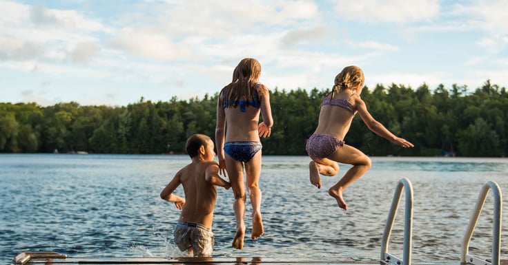 Kids jumping into lake swimming